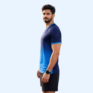 A man stands sideways, wearing a blue gradient athletic shirt and black shorts, looking confident. He has a watch on his wrist against a light blue background.