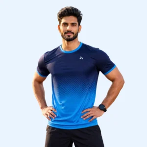Man in a blue gradient athletic shirt and black shorts, standing confidently with hands on hips. The background is plain light blue, conveying a fitness theme.
