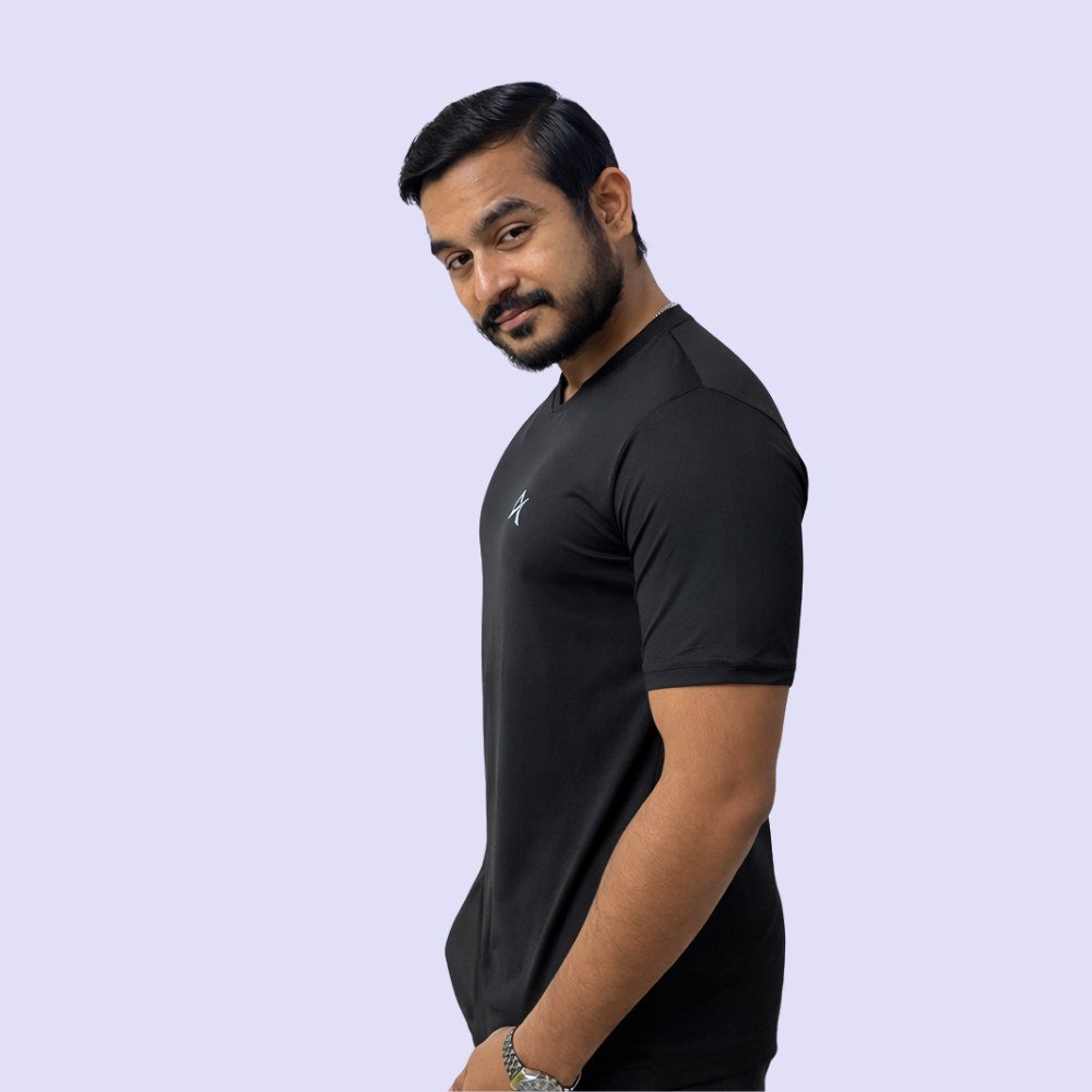 A man in a black V-neck T-shirt stands confidently against a white background, exuding a casual and stylish appearance.